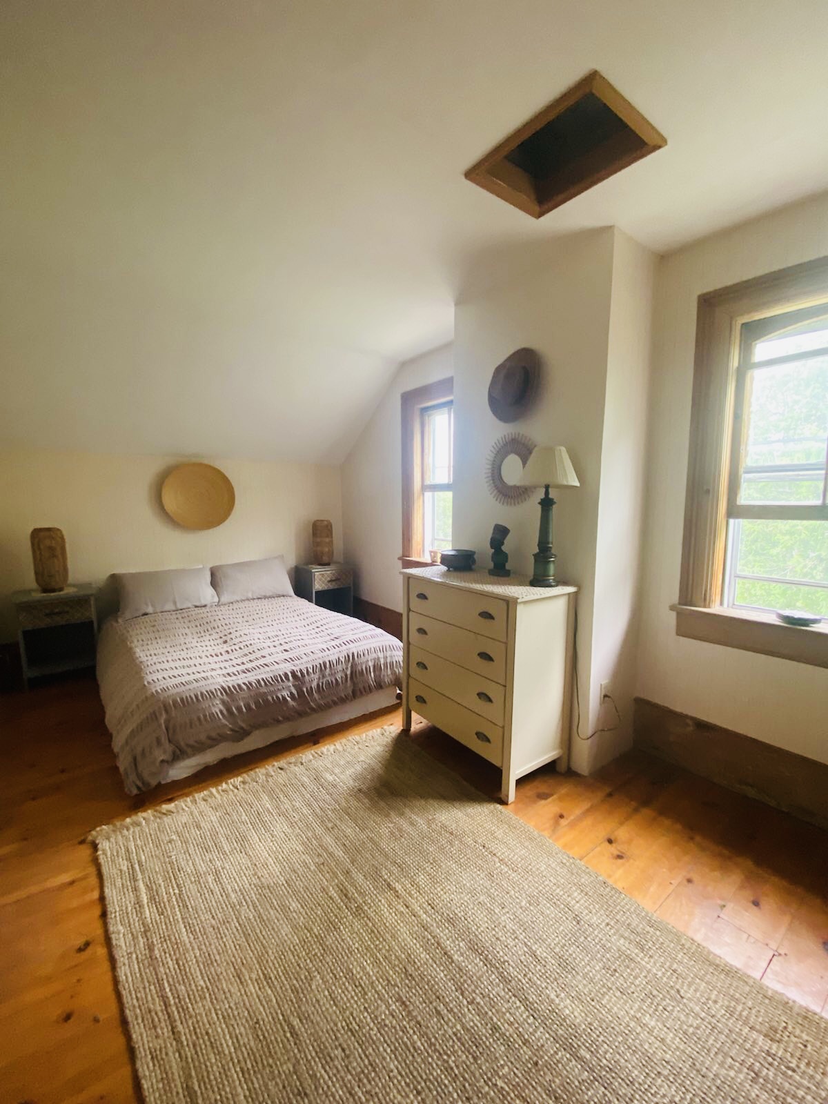 Sunlit farmhouse bedroom with king bed and woven rug